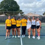 Group photo of FNU's women's tennis team in front of a net.